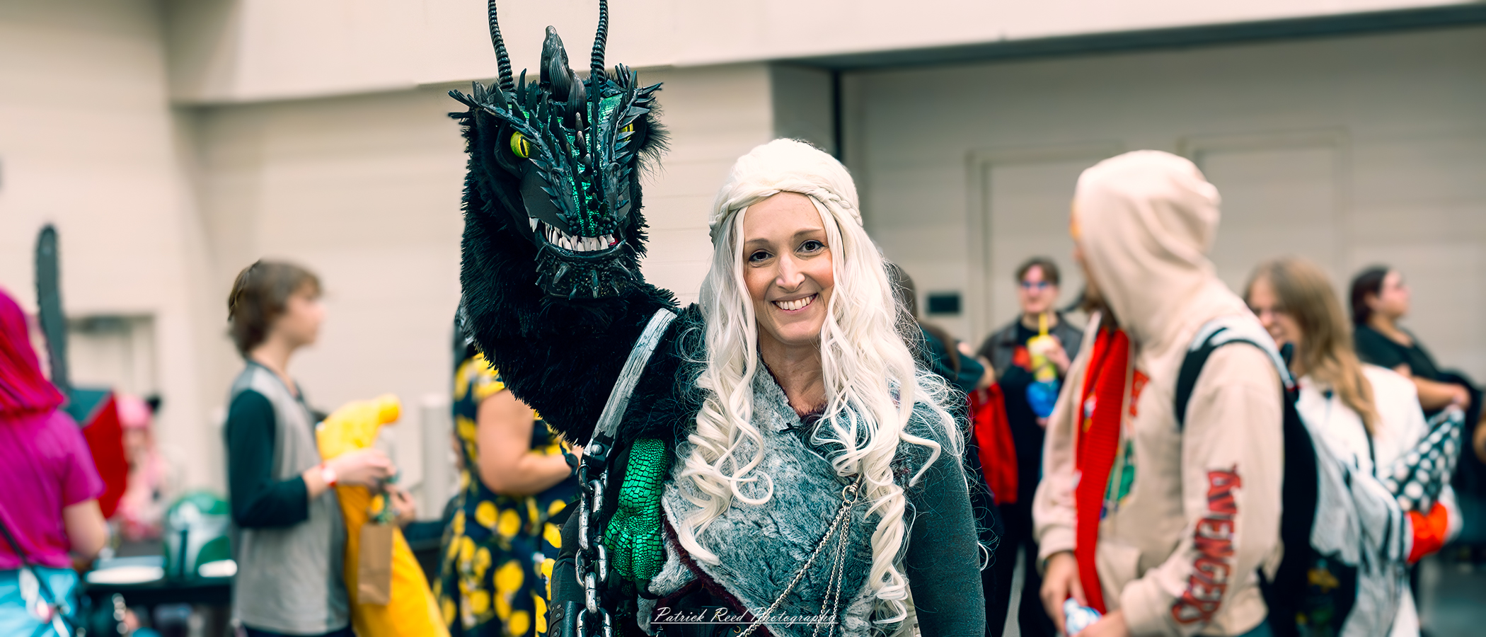 "Cosplayer dressed as Daenerys Targaryen from Game of Thrones, wearing a flowing gown with intricate detailing, platinum blonde hair styled in her signature braids, and a confident, regal expression, embodying the Mother of Dragons."